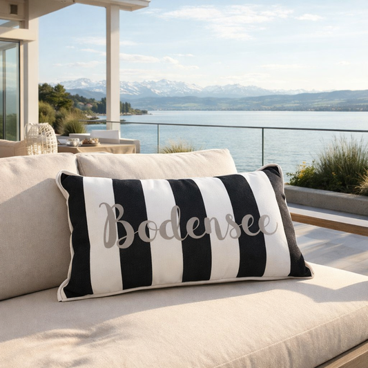 Gartenkissen schwarz weiß gestreift mit silbernen Schriftzug Bodensee auf Gartenlounge mit Terrasse am Bodensee und Blick auf die Alpen.