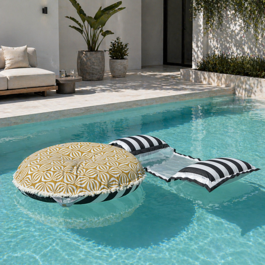 Wasserhängematte mit Netz in Schwarz/Weiß gestreift von chillisy in 170 cm und 200 cm Länge erhätlich, hergestellt in Deutschland. Badeinsel Goldfalter mit Houles Fransen. Dargestellt am Pool in modernem Ambiente.