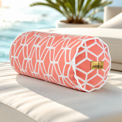 Korallenfarbene Designer-Nackenrolle Crystal Gold von chillisy® mit weißem geometrischem Muster, weißem Keder und Goldlabel auf einer exklusiven Pool-Lounge.
