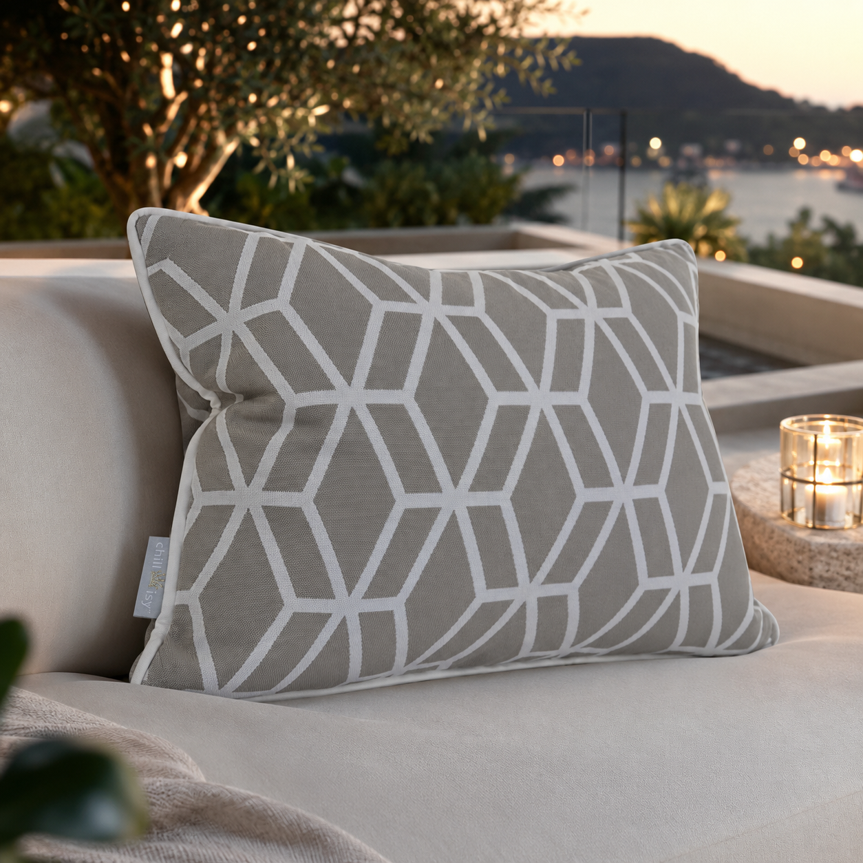 Designer Outdoor-Kissen Crystal Gold von chillisy® in Hellgrau mit weißem geometrischem Muster auf einer exklusiven Lounge am Meer.