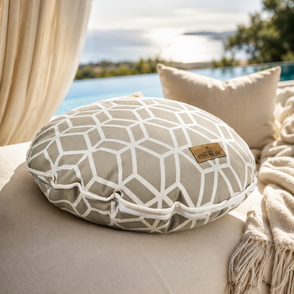 Designer-Rundkissen Crystal Gold von chillisy® in Hellgrau mit weißem geometrischem Muster auf einer luxuriösen Outdoor-Lounge mit Infinity-Pool.