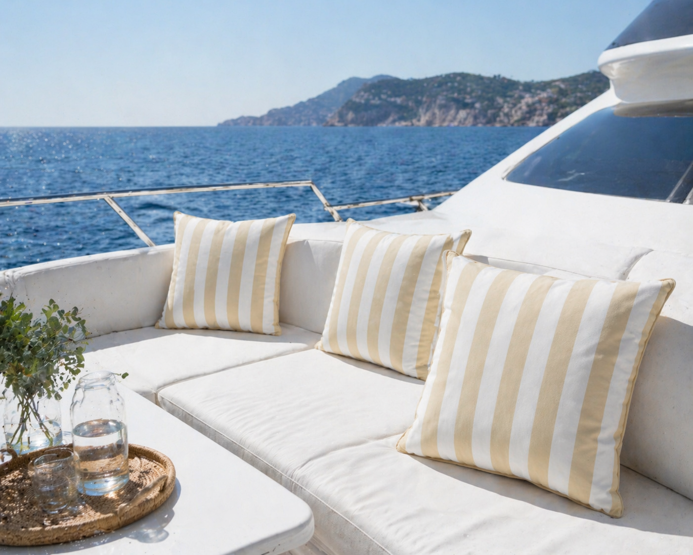 Wetterfestes Yachtkissen mit sandfarbenen und weißen Blockstreifen 60x60 cm im maritimen Design hergestellt von chillisy in Deutschland. Präsentiert an Deck einer Yacht mit Meerblick.