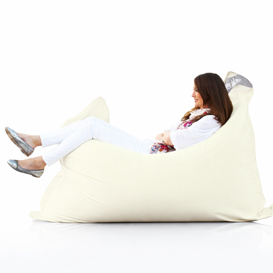 Frau entspannt auf cremefarbenem chillisy Premium Sitzsack – luxuriöser Designer Sitzsack für Indoor, Terrasse und Garten, hergestellt in Deutschland.