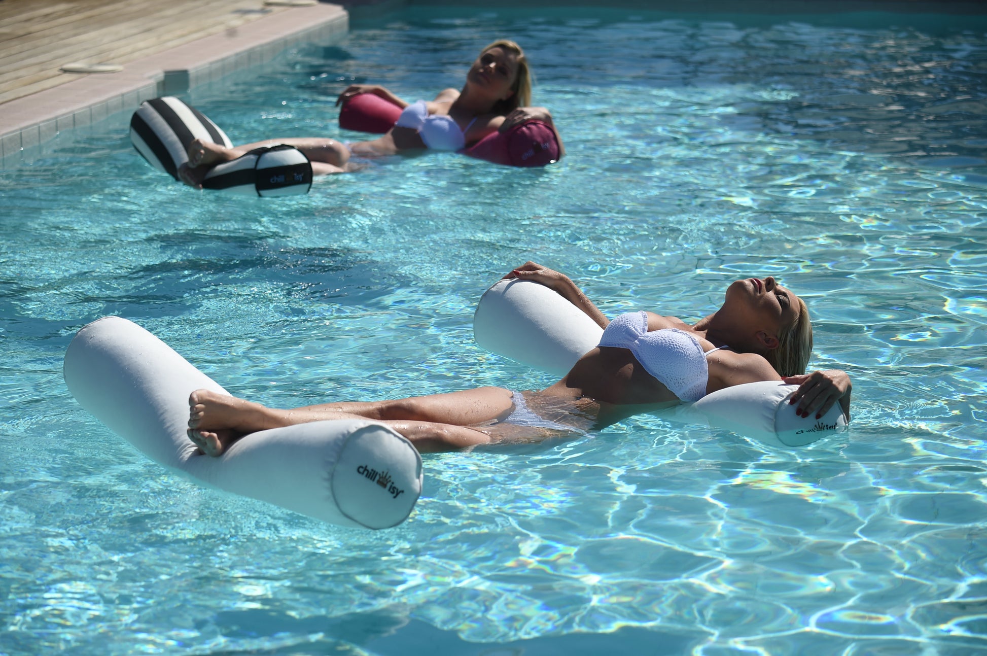 Zwei Frauen liegen auf Schwimmnudeln im Pool