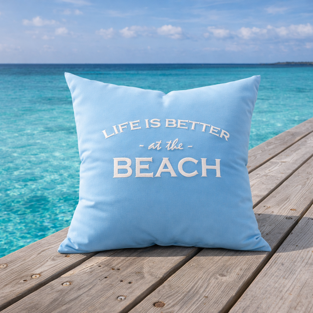 Dekokissen Aqua Blau mit weißer Stickerei LIFE IS BETTER AT THE BEACH auf Holzsteg am Meer