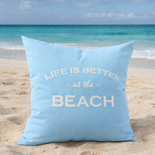 Dekokissen Aqua Blau mit weißer Stickerei LIFE IS BETTER AT THE BEACH am Sandstrand mit Meerblick