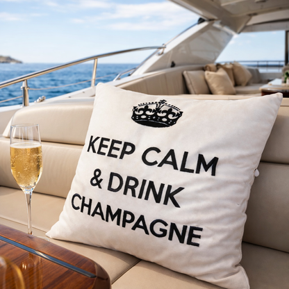 Wollweisses bzw. cremeweisses Dekokissen mit schwarzer Krone und Schriftzug KEEP CALM & DRINK CHAMPAGNE auf einer Motoryacht