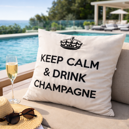 Wollweisses bzw. cremeweisses Dekokissen mit schwarzer Krone und Schriftzug KEEP CALM & DRINK CHAMPAGNE auf der Terrasse am Pool