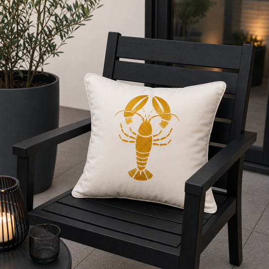 Weißes goldenes Hummer Dekokissen für Outdoor und indoor von chillisy hergestellt in Deutschland. Auf schwarzen Gartenstuhl.