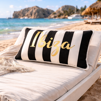 Ibiza Kissen Schwarz Weiß gestreift mit goldenem Aufdruck für Outdoor und Indoor, hergestellt von chillisy in Deutschland - auf Sonnenliege am Strand mit Meer im Hintergrund.