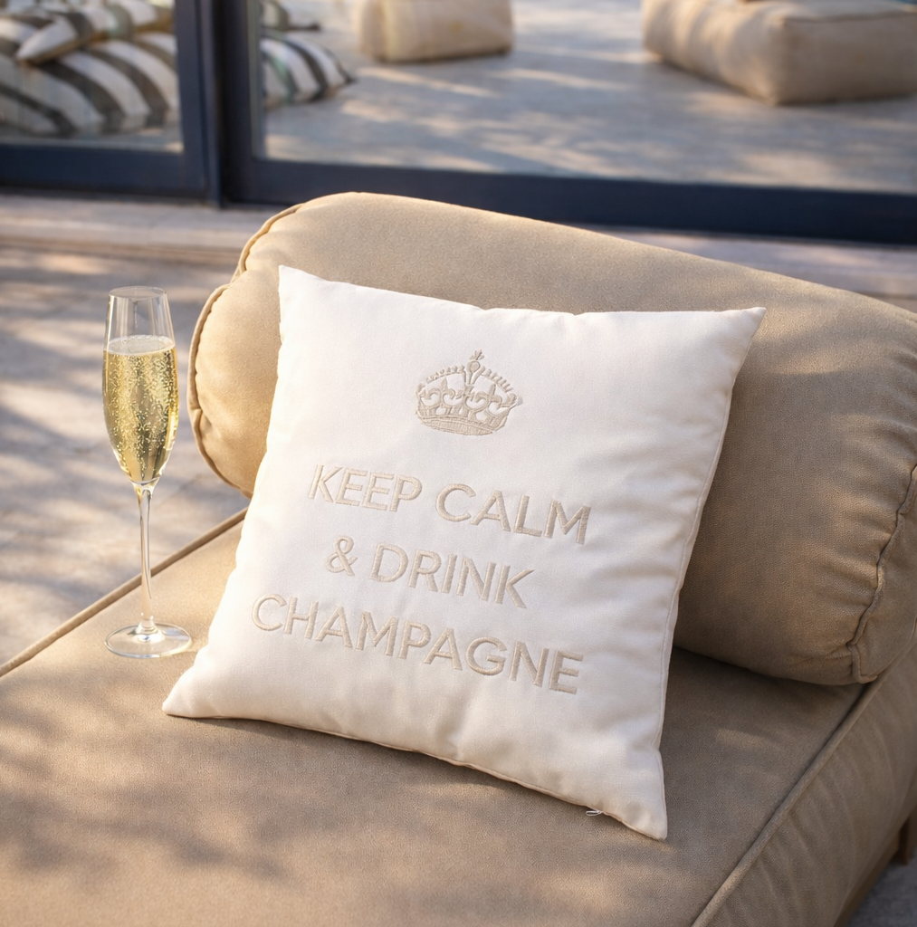 Luxuriöse Outdoor-Kissen „Keep Calm & Drink Champagne“ auf beigem Daybed am Pool – wasserfestes Premium Gartenkissen für Terrasse, Pool und Yacht.