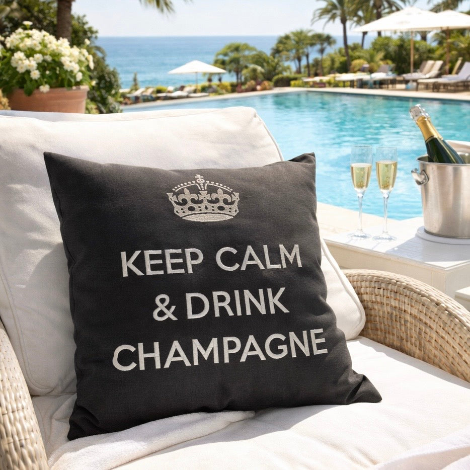 Anthrazit farbenes Kissen mit Krone und Schriftzug KEEP CALM & DRINK CHAMPAGNE am Pool