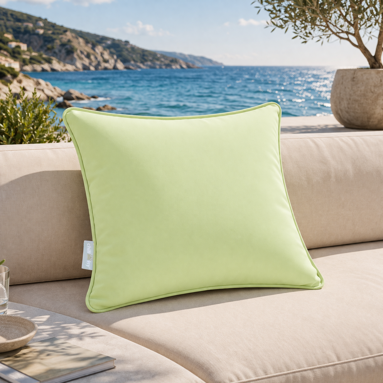 Gartenkissen in Lindgrün von chillisy hergestellt in Deutschland auf Gartenlounge mit Meer und Küste im Hintergrund.