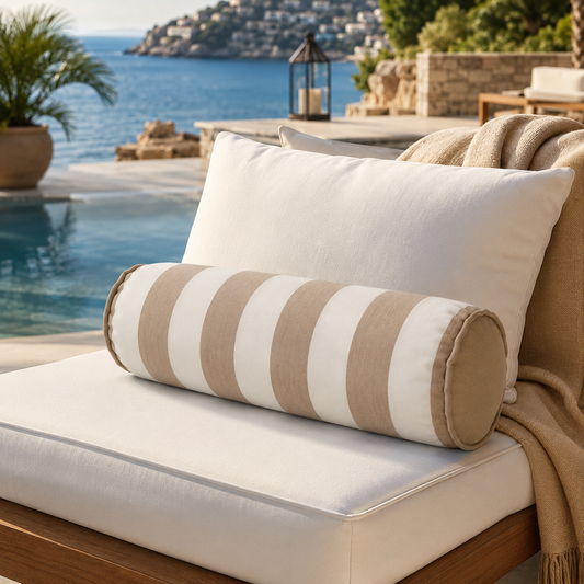 Luxuriöse Outdoor-Nackenrolle (Bolster) mit breiten Beige-Weiß-Blockstreifen auf einer eleganten weißen Gartenlounge am Pool. Hochwertiges Designer-Kissen in stilvoller Resort-Atmosphäre mit Meerblick – ideal für Terrasse, Garten und exklusiven Outdoor-Wohnbereich.