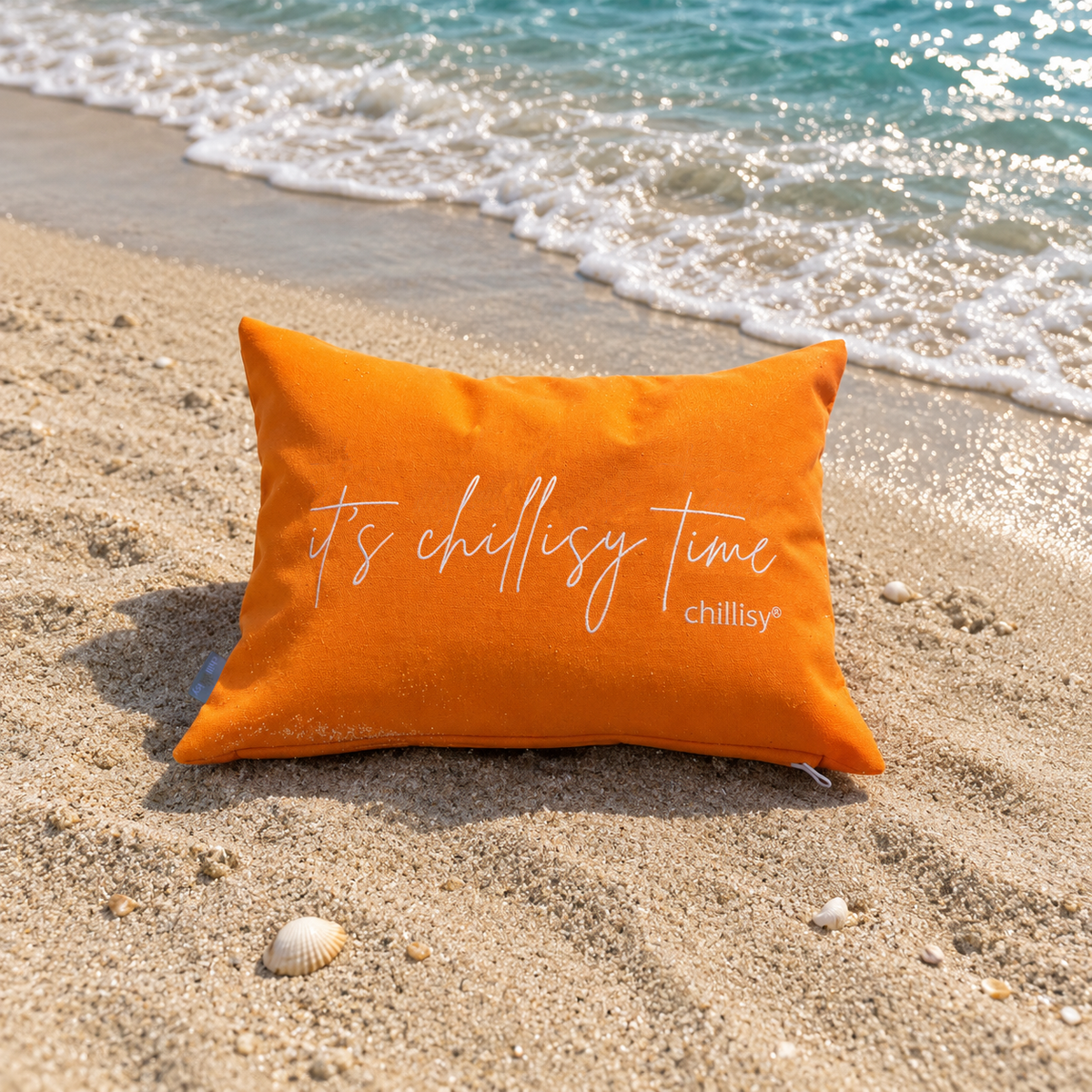 Orange farbenes Piccolino Kissen am türkis farbenen Strand mit Schriftzug: it's chillisy time von chillisy.