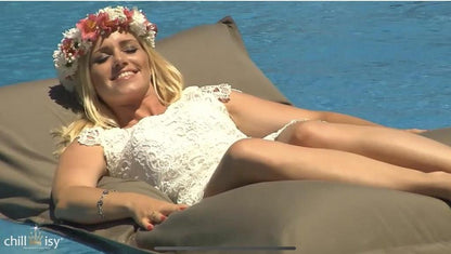 Frau im Kleid und mit Blumenkranz entspannt auf einem Pool Sitzssack von chillisy, hergestellt in Deutschland. 