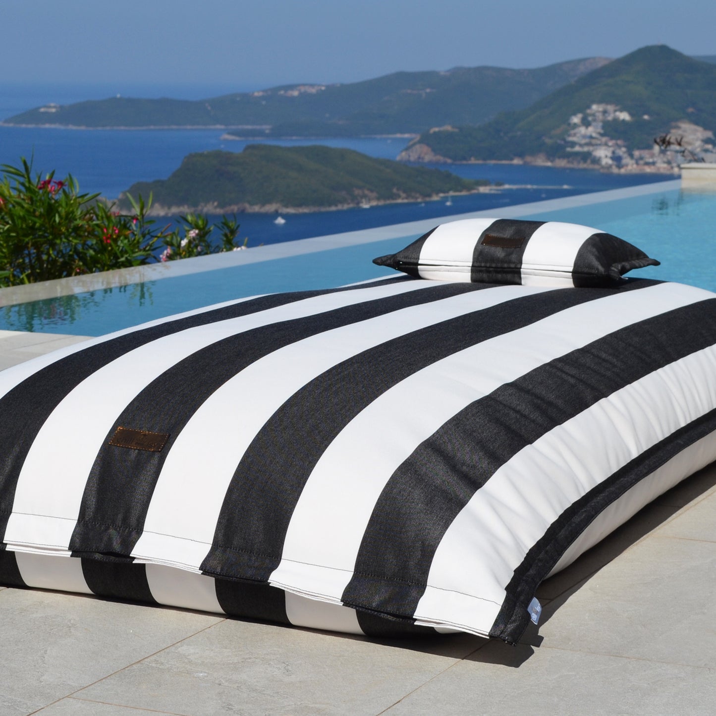 Schwarz weiß gestreifter Pool Sitzsack Lungo von chillisy am Pool liegend.