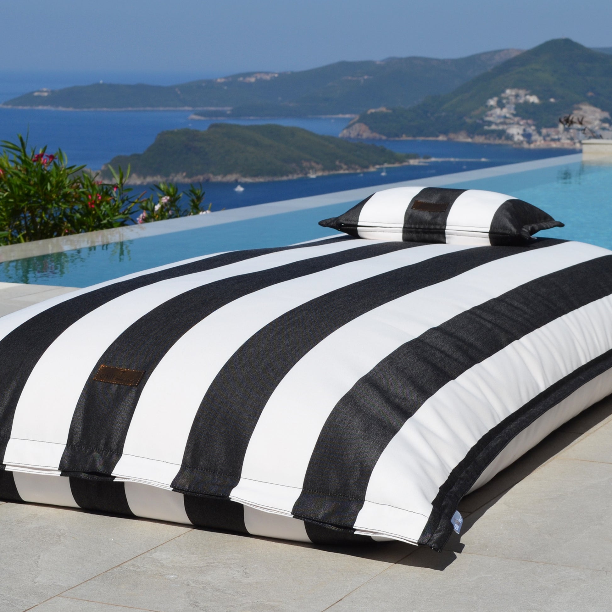 Schwarz weiß gestreifter Pool Sitzsack Lungo von chillisy am Pool liegend.
