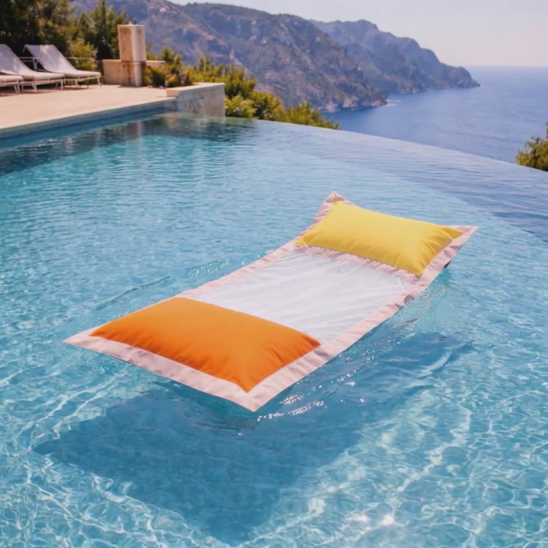 Wasserhängematte mit Netz in orange und gelb von chillisy im Pool mit Meerblick liegend.