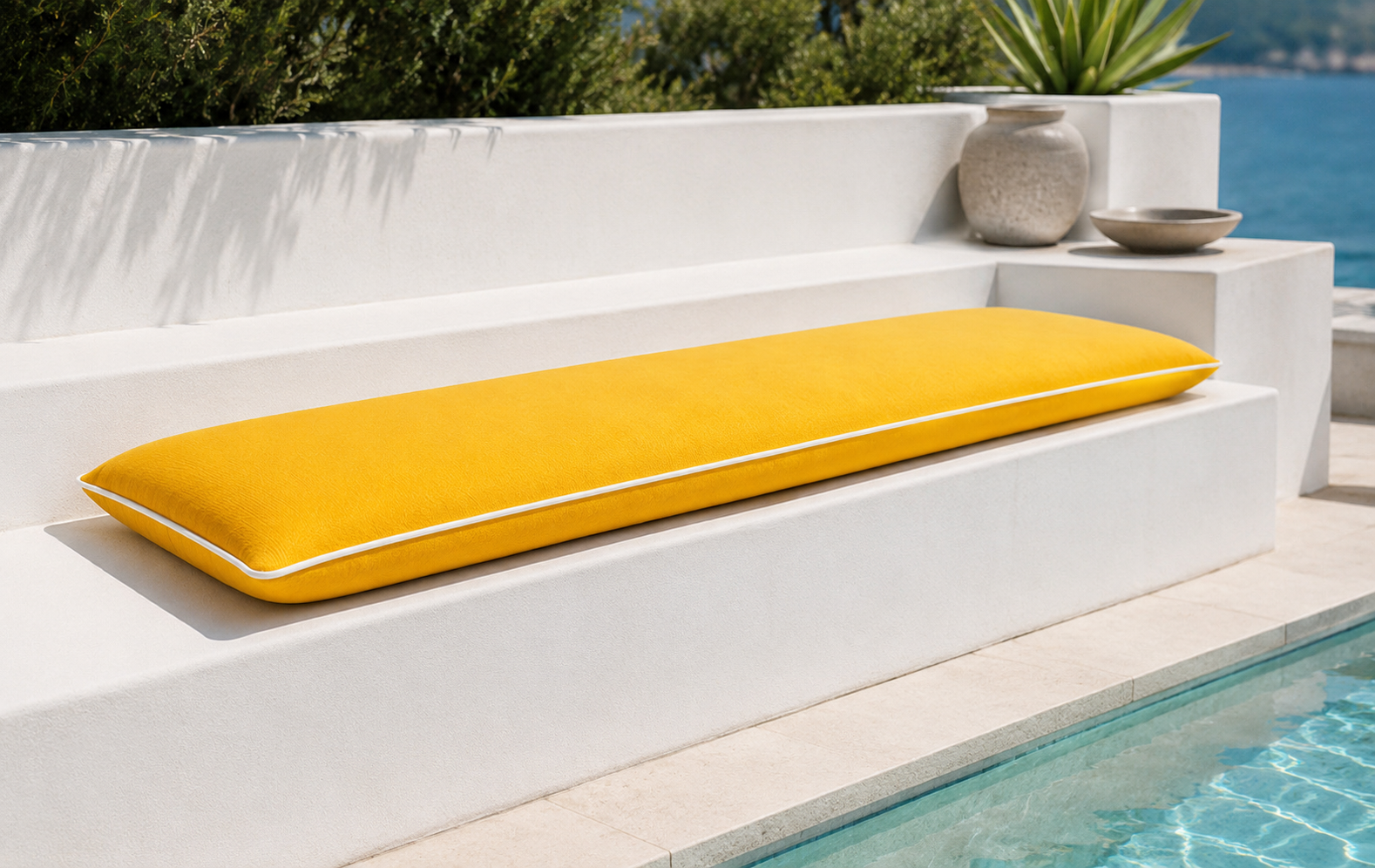 Lange Sonderanfertigung eines gelben chillisy® Outdoor Sitzkissen Summertime mit weißem Keder auf moderner Terrassenbank am Pool – hochwertige Gartenkissen Made in Germany