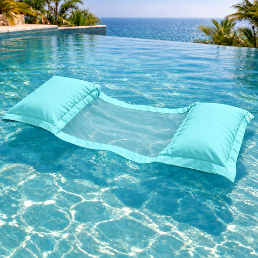 chillisy® Wasserhängematte in hellem Türkis mint mit transparentem Netz, schwimmend in einem türkisblauen Infinity-Pool mit Meerblick.