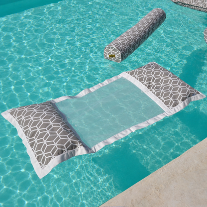Graue Wasserhängematte mit geometrischem Muster und passender Nackenrolle, schwebend auf kristallklarem türkisfarbenem Poolwasser – hochwertige Detailaufnahme für luxuriöse Entspannung im Pool.