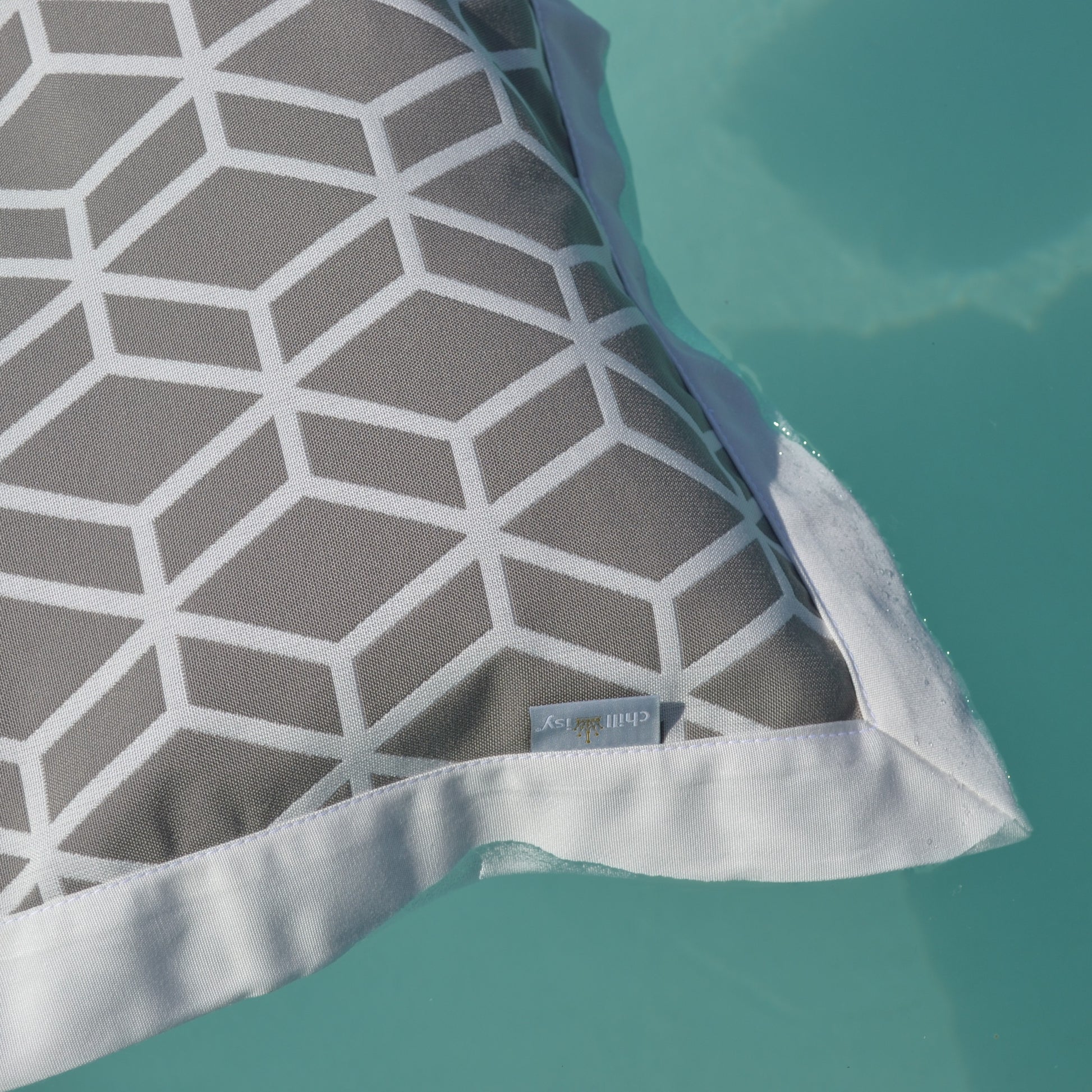 Graue Wasserhängematte von chillisy im Detail mit geometrischem Muster schwebend auf türkisfarbenem Poolwasser – hochwertige Detailaufnahme für luxuriöse Entspannung im Pool. Made in Germany.