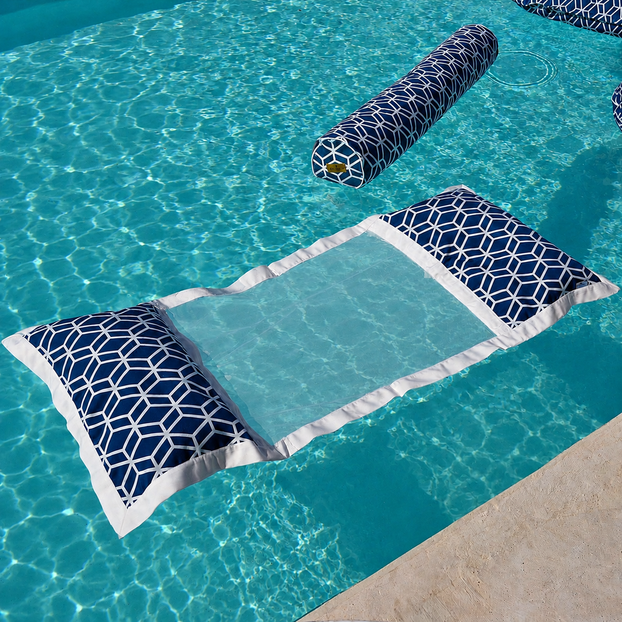 Luxuriöse schwimmende Wasserhängematte in Marineblau und Weiß mit geometrischem Muster im türkisblauen Pool. Die Netzliege lässt den Körper angenehm im Wasser schweben und eignet sich ideal zum Entspannen an heißen Sommertagen im Pool, am See oder im Meer.